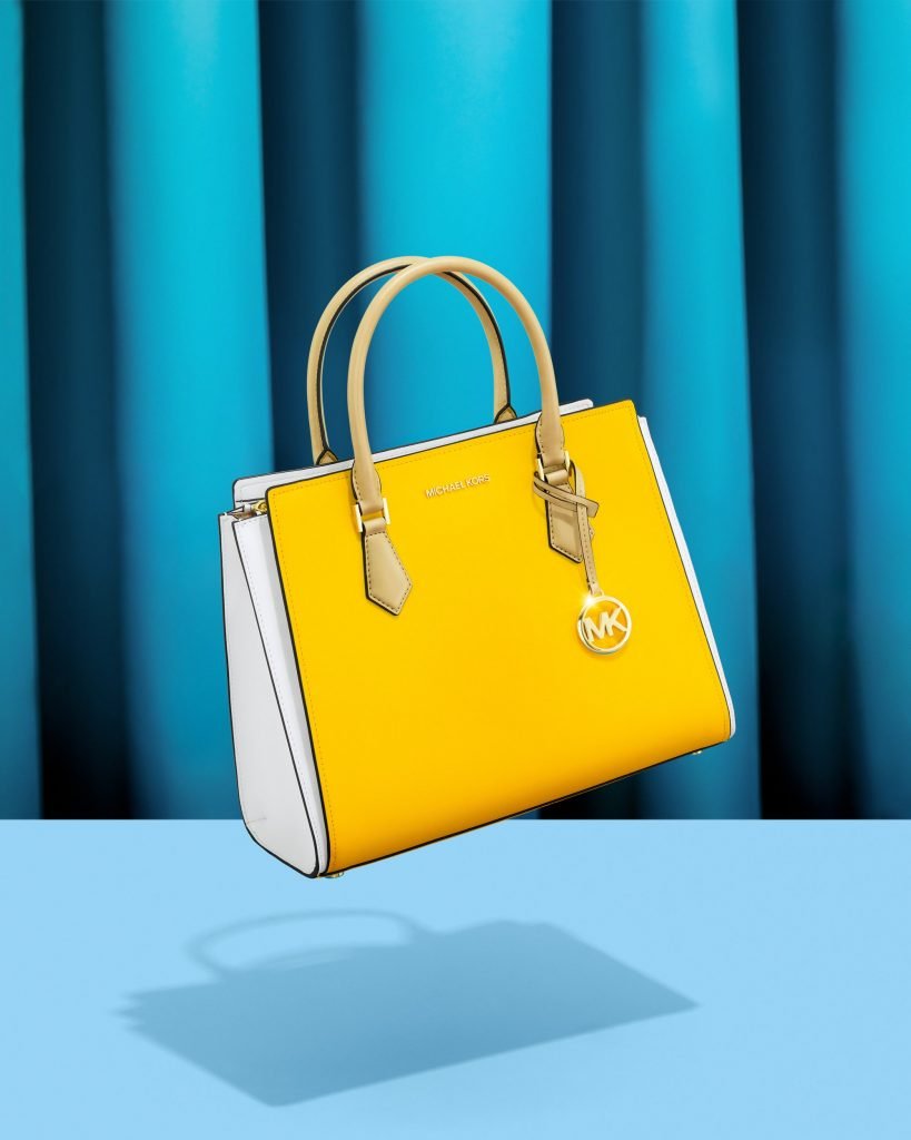 Creative Commercial photography of Michael Kors yellow bag with a blue background.