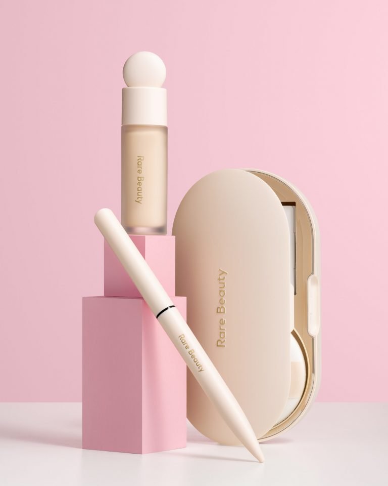 Creative photography of the "Rare Beauty" cosmetic set with the pink background and two small cubes to support Liquid Touch Weightless Foundation and Liquid Liner